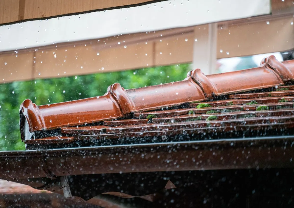 Rain running off a tiled roof into a gutter