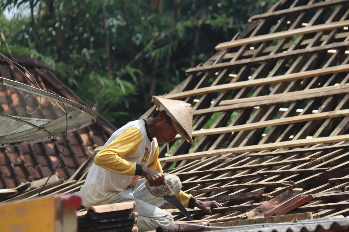 A roofer laying tiles on a pitched roof