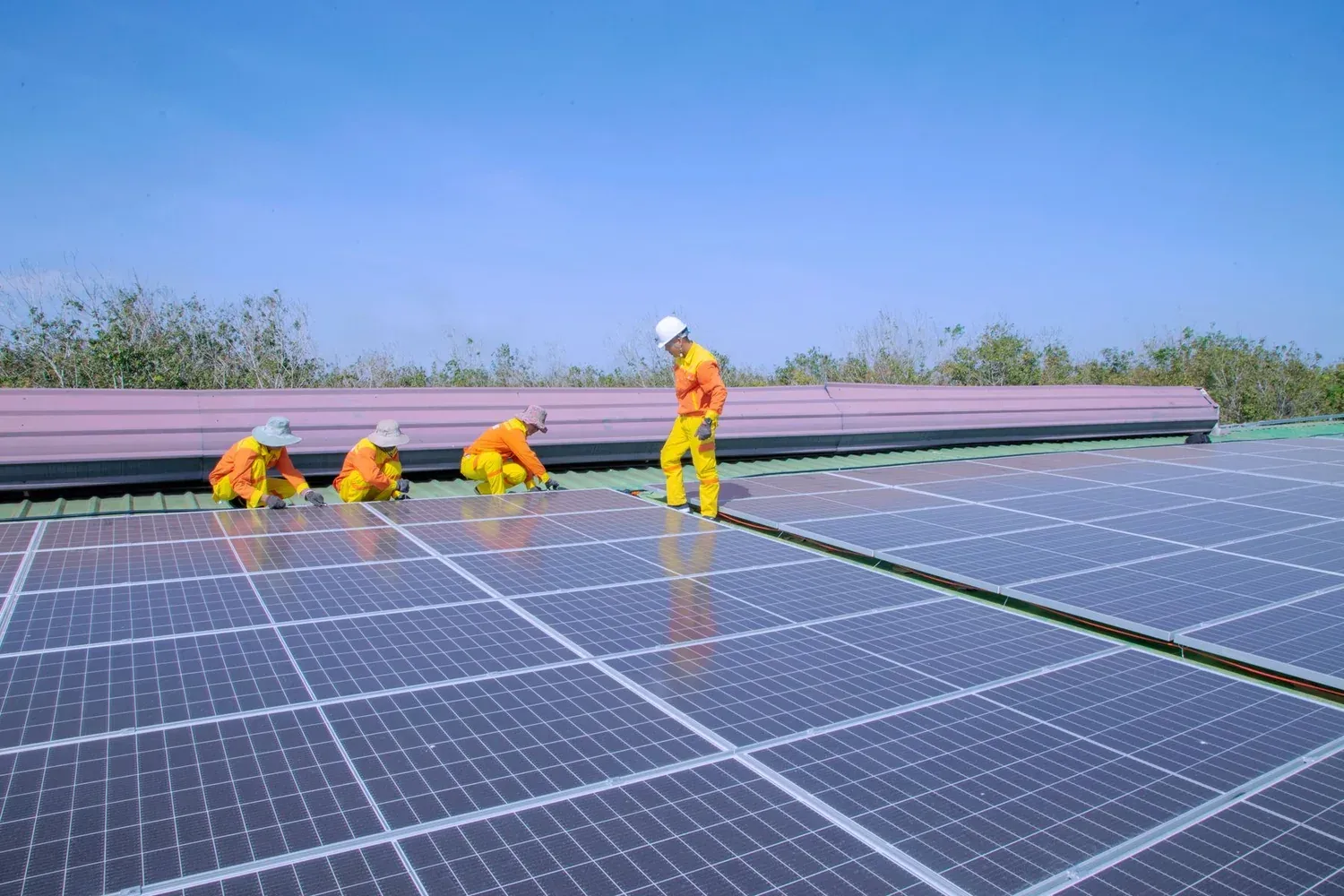 Technicians installing solar panels across a large rooftop
